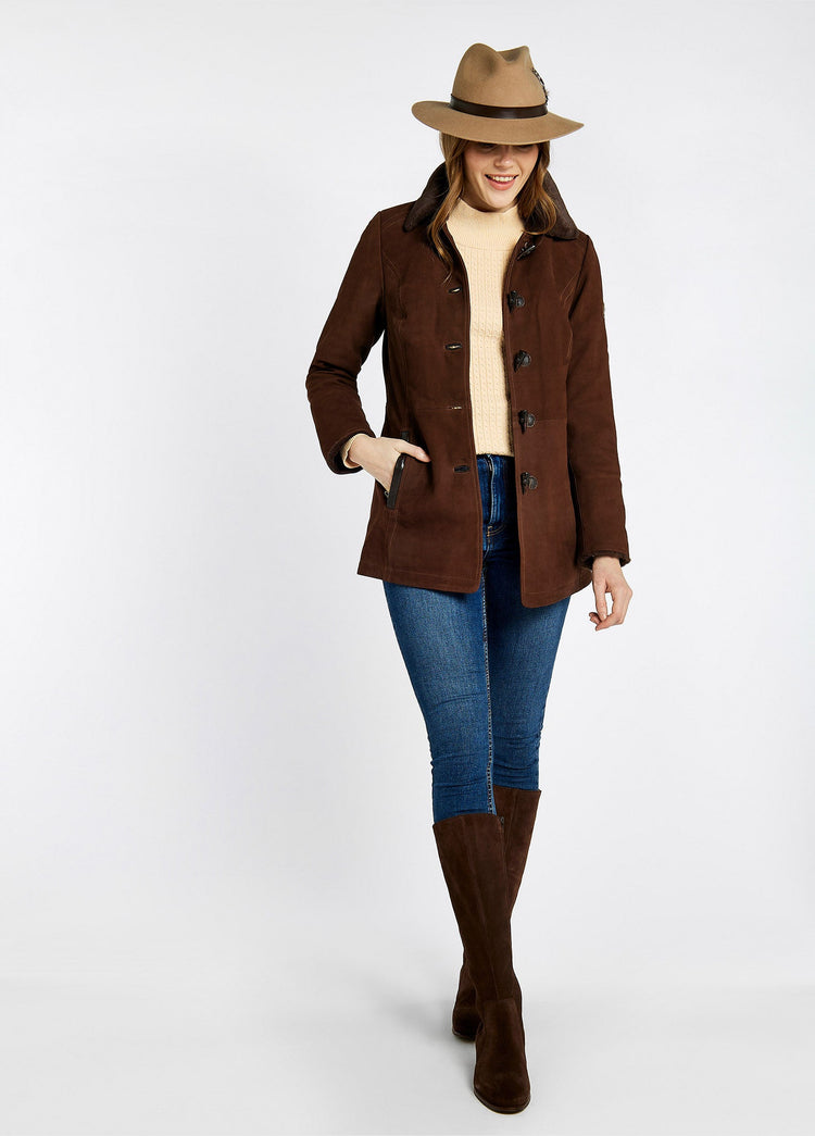 Model wearing a women's Dubarry Clarke leather jacket opened, the walnut brown coloured jacket has a fur collar and toggle buttons. The model is also wearing a beige hat, a cream jumper, blue jeans and brown boots